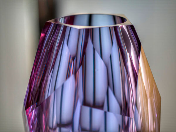 top detail of pink and purple hue crystal faceted vase hand-cut entirely by glass artisan place on top of table centrepiece