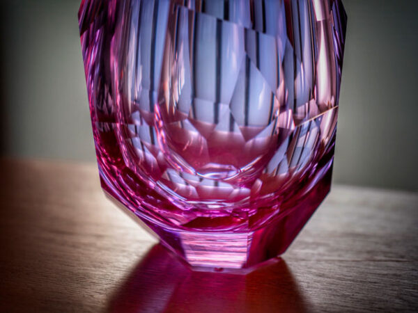 bottom detail of pink and purple hue crystal faceted vase hand-cut entirely by glass artisan place on top of table centrepiece