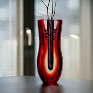 a red glass sommerso style bud vase on top of table